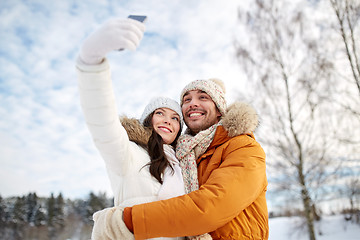 Image showing happy couple taking selfie by smartphone in winter