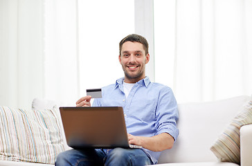 Image showing smiling man with laptop and credit card at home