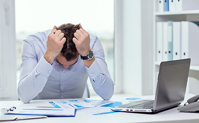 Image showing stressed businessman with papers in office