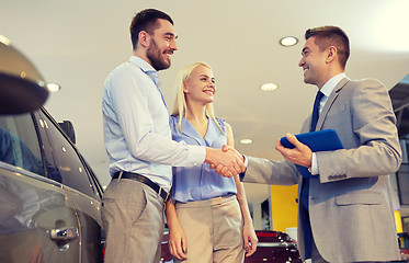 Image showing happy couple with car dealer in auto show or salon