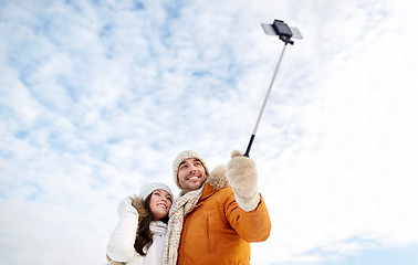 Image showing happy couple taking selfie by smartphone in winter