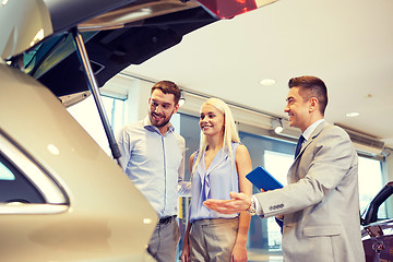 Image showing happy couple with car dealer in auto show or salon