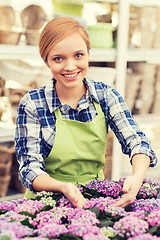 Image showing happy woman taking care of flowers in greenhouse