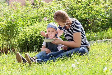 Image showing Mother feeding her son on the grass