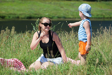 Image showing Mother and son playing with grass on the meadow