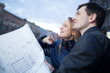 Image showing Couple holding blueprints admiring building