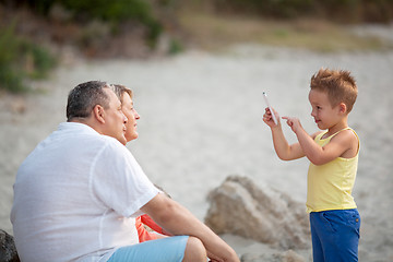 Image showing Boy taking phone photo of grandparents outdoor