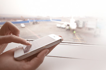 Image showing Woman using smart phone by the window at aiport