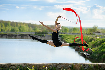 Image showing Gymnast girl doing leg-split in a jump with ribbon