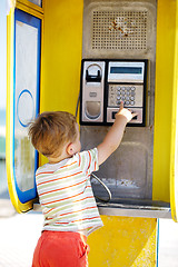 Image showing Young boy talking to the phone in a booth