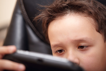 Image showing Boy tired of playing his portable game console.