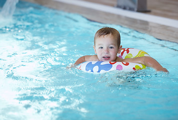 Image showing Kid learns to swim using a plastic water ring