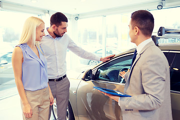 Image showing happy couple with car dealer in auto show or salon