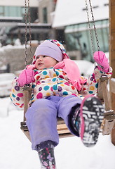 Image showing little girl at snowy winter day swing in park