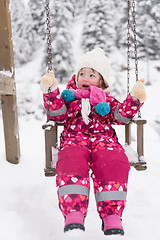 Image showing little girl at snowy winter day swing in park