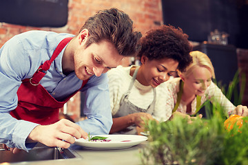 Image showing happy friends cooking and decorating dishes