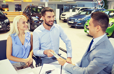 Image showing happy couple with car dealer in auto show or salon