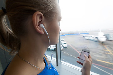 Image showing Woman listening to music by the window at airport