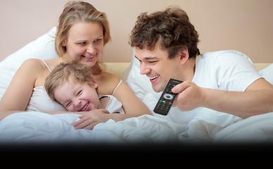 Image showing Happy family lying in bed watching television