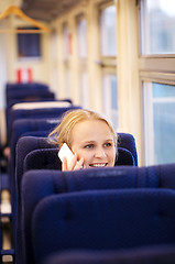 Image showing Smiling woman talking on the phone in train.