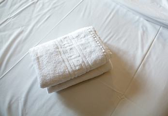 Image showing Pile of white clean towels on the bed
