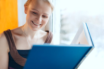 Image showing Young smiling woman reading a book