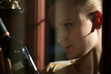 Image showing Woman taking a bottle of wine from liquor cabinet