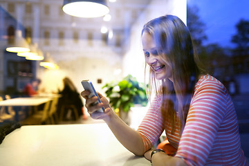 Image showing Young woman sitting in a restaurant using mobile