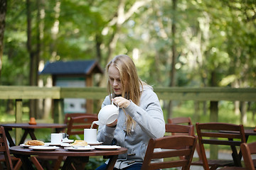 Image showing Young woman enjoying a pot of tea