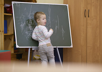 Image showing Creative little boy drawing on a chalkboard