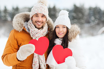 Image showing happy couple with red hearts over winter landscape