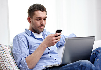 Image showing man with smartphon and laptop computer at home