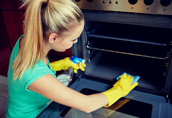 Image showing happy woman cleaning cooker at home kitchen