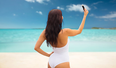 Image showing young woman taking selfie with smartphone on beach