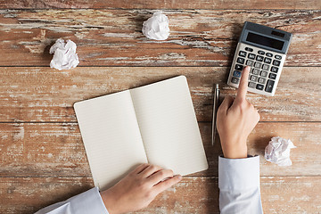 Image showing close up of hands with calculator and notebook