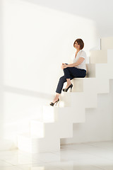 Image showing Elegant adult woman smiling while sitting on steps