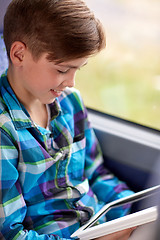 Image showing happy boy with tablet pc in travel bus or train