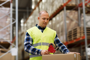 Image showing man in safety vest packing box at warehouse