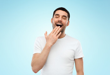 Image showing tired sleepy yawning man over blue background