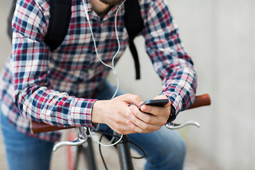 Image showing hipster man in earphones with smartphone and bike