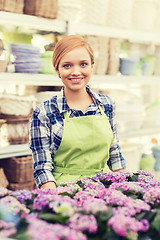 Image showing happy woman with flowers in greenhouse