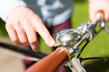 Image showing close up of male hand ringing bell on bike wheel