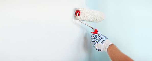 Image showing close up of male in gloves painting wall