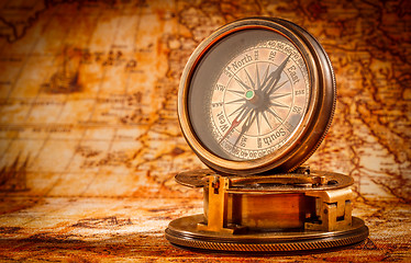 Image showing Vintage compass lies on an ancient world map.