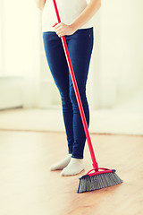 Image showing close up of woman legs with broom sweeping floor