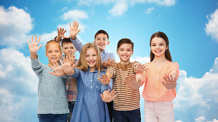 Image showing happy children waving hands over blue sky