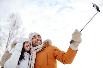 Image showing happy couple taking selfie by smartphone in winter