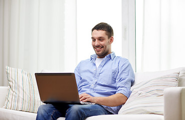 Image showing smiling man working with laptop at home