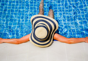 Image showing Woman in straw hat relaxing swimming pool