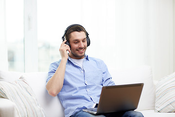 Image showing smiling man with laptop and headphones at home